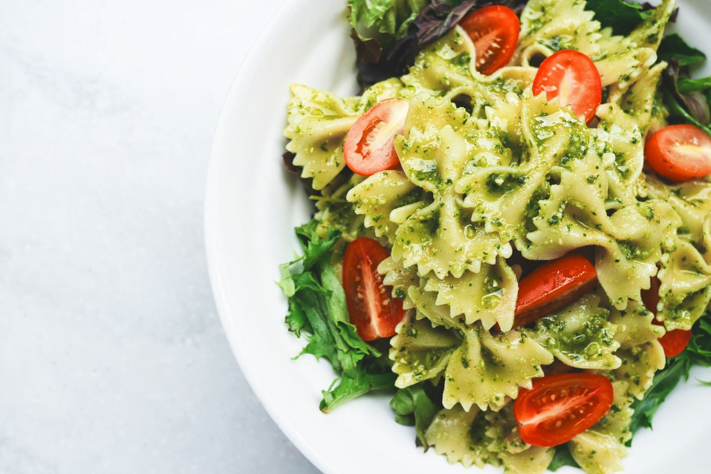 A bowl of pesto pasta with cherry tomatoes